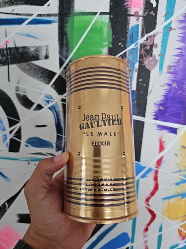 Gold perfume bottle and packaging of Jean Paul Gaultier Le Male Elixir on a white background